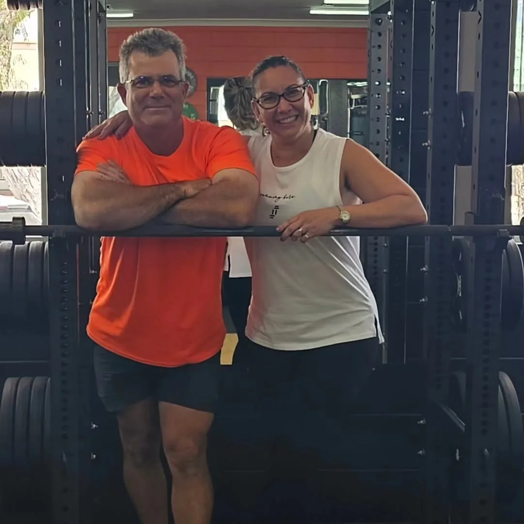Christian and Yvette Lando, the owners of Get Fit Burdekin, leaning on a loaded barbell in the power rack at their Home Hill gym