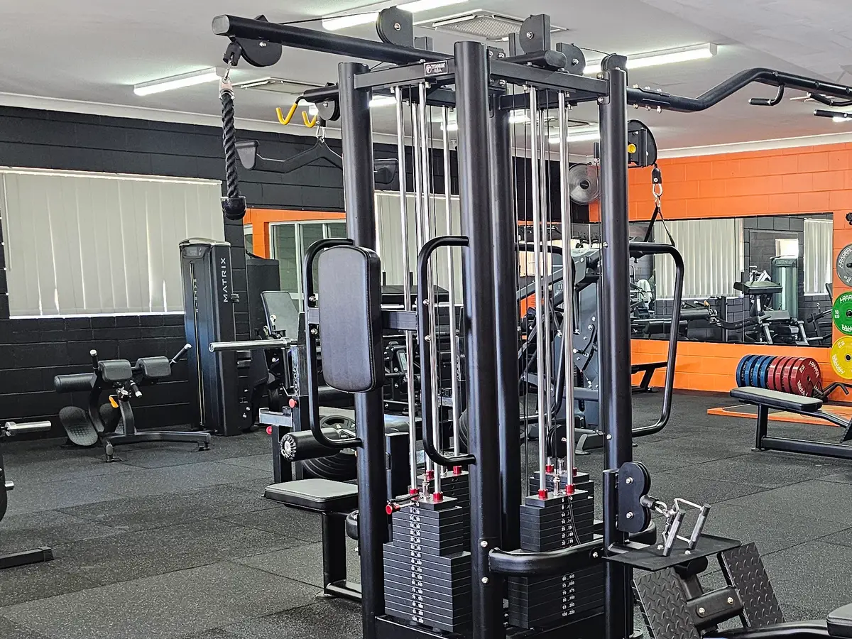 A multi-station cable machine on the main floor at Get Fit Burdekin, with the orange wall and mirrors behind