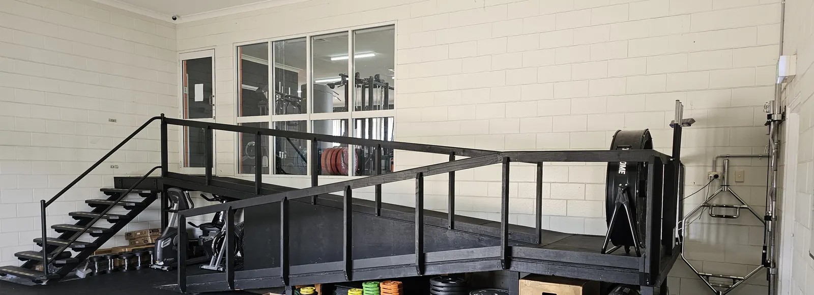 The group fitness area at Get Fit Burdekin, with the raised platform and stairs at one end and bumper plates and plyo boxes stored underneath