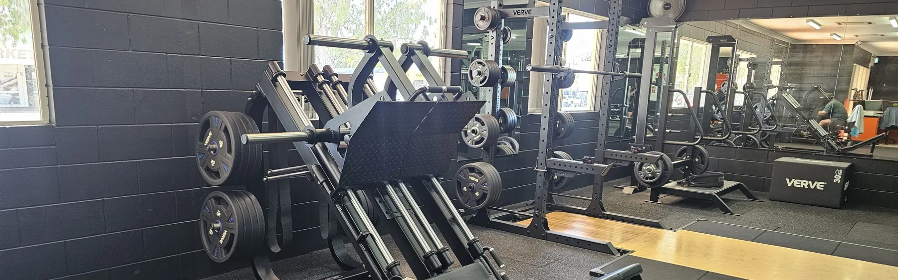 A plate-loaded leg press in front of the squat racks along the window wall at Get Fit Burdekin