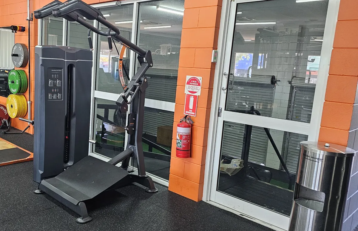 A pin-loaded calf raise and hack squat machine beside the glass doors at Get Fit Burdekin
