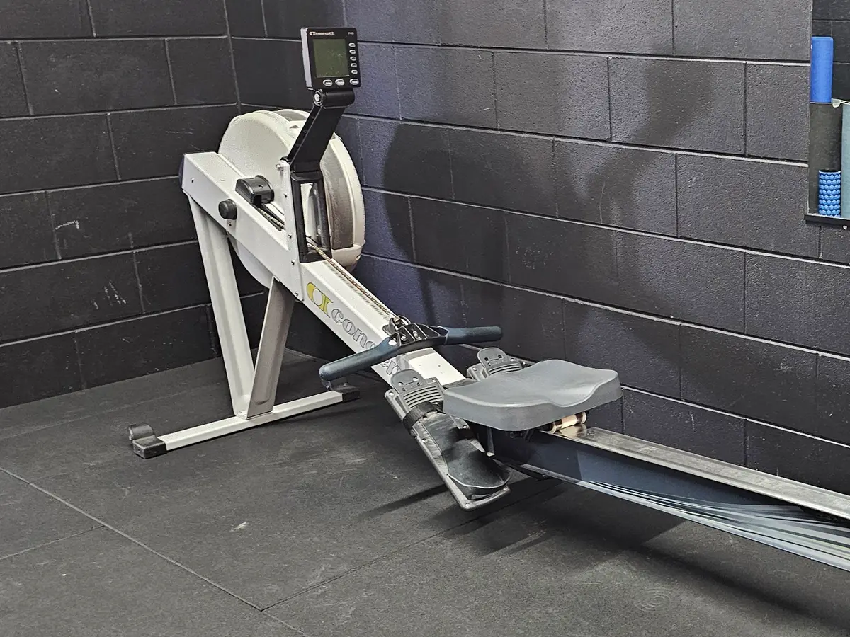 A rowing machine on the rubber floor against the black brick wall at Get Fit Burdekin