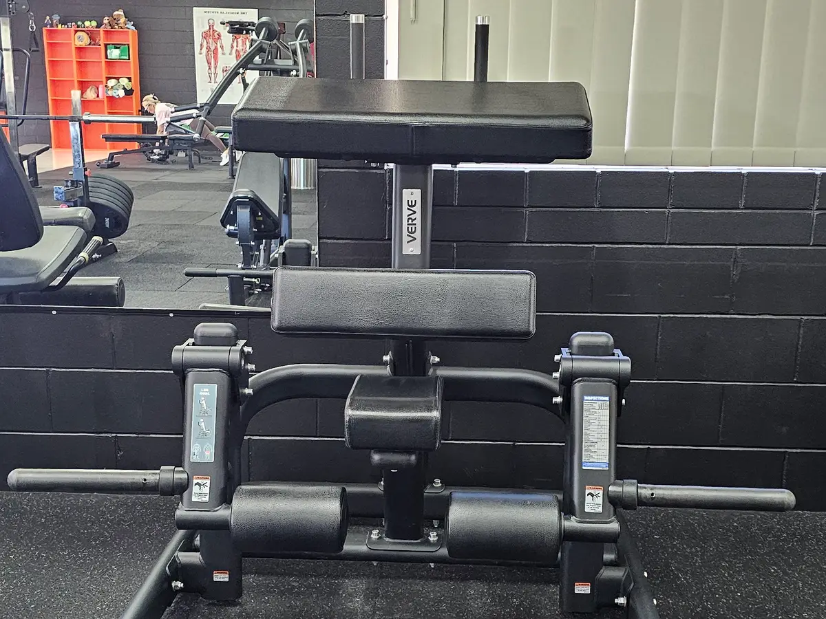 A plate-loaded standing leg curl in front of the mirrored wall at Get Fit Burdekin