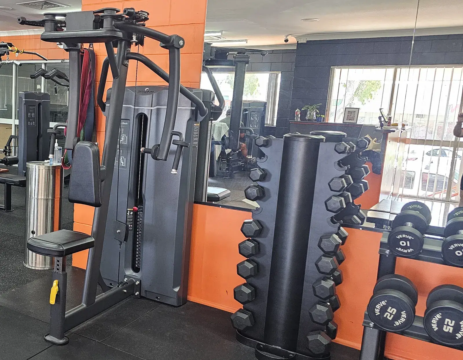 A pin-loaded pec deck beside a dumbbell tower on the main floor at Get Fit Burdekin, with cable machines behind