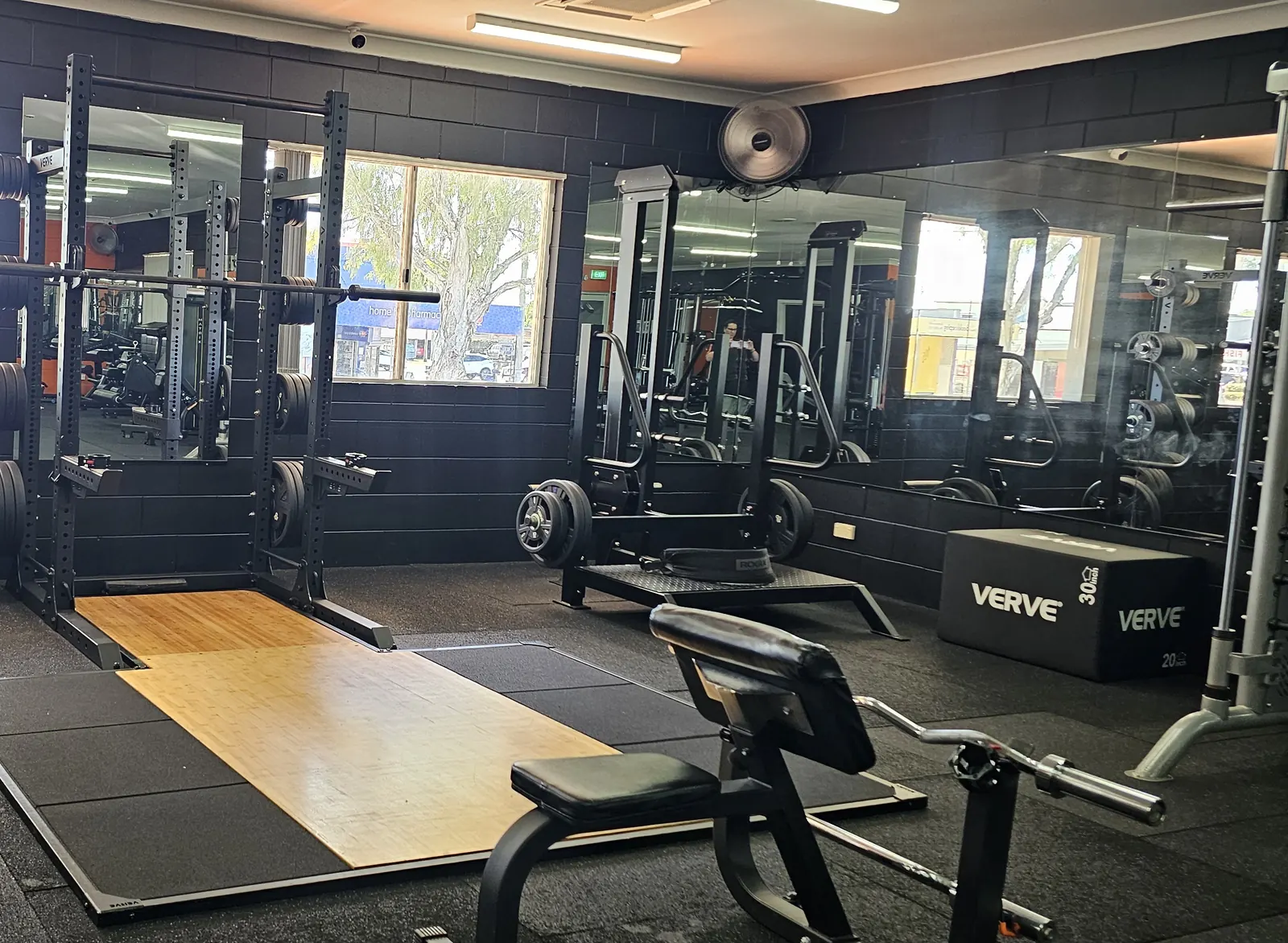 A squat rack over a timber lifting platform at Get Fit Burdekin, with a bench, plyo boxes and the mirrored wall behind